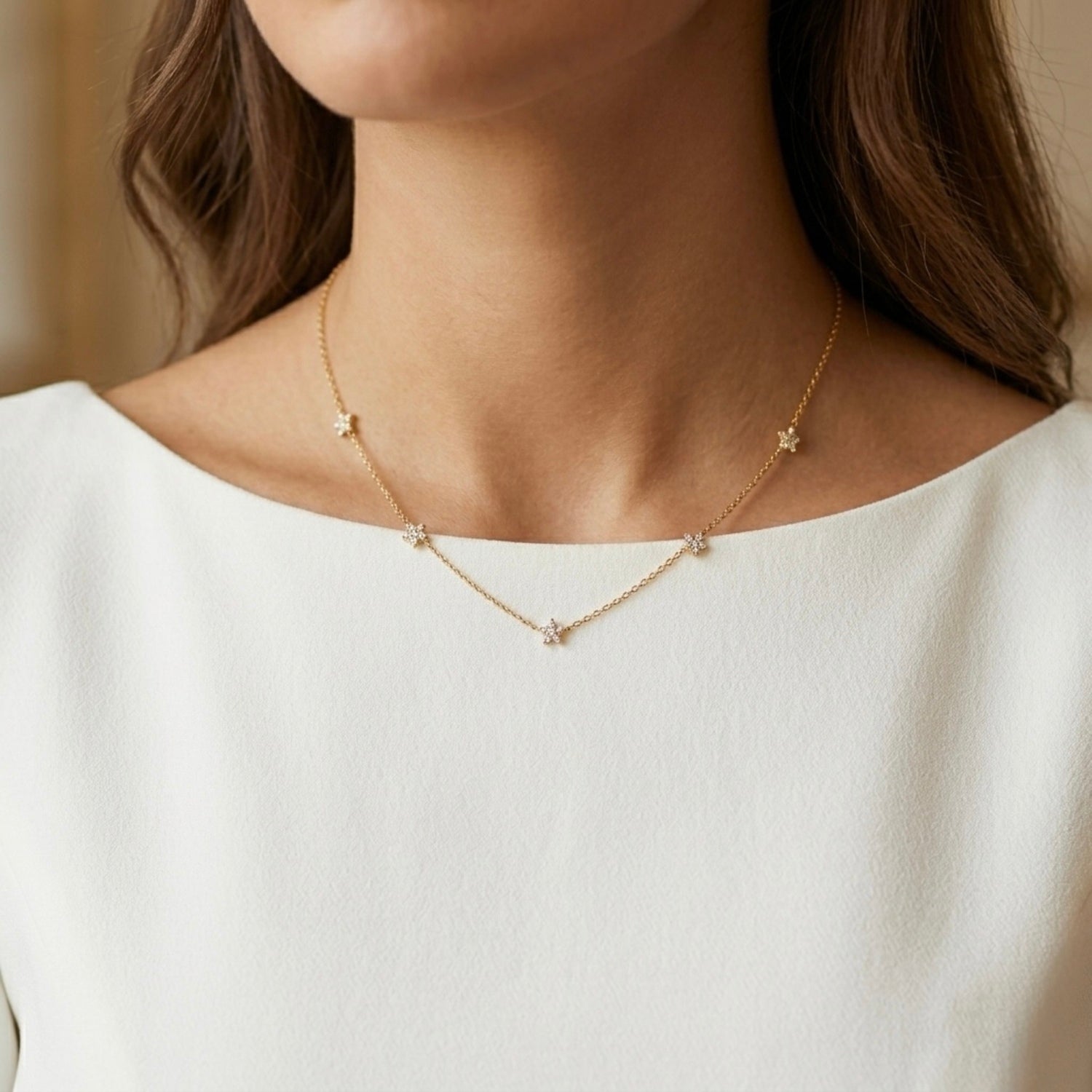 A gold-plated stainless steel chain for women featuring multiple small crystal-encrusted star stations, shown on a model