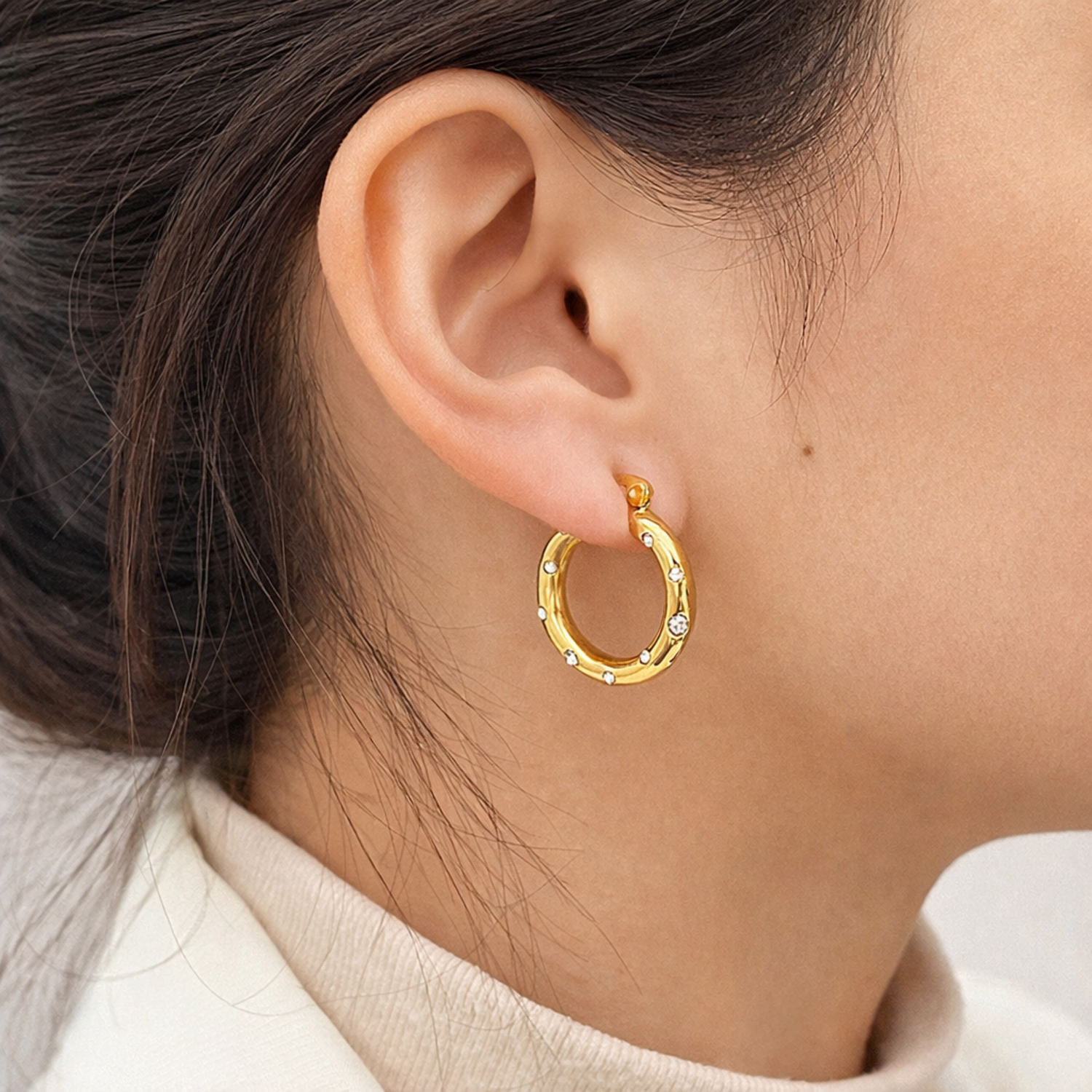 A gold-plated thick hoop earrings for women featuring scattered clear crystals, shown on a model