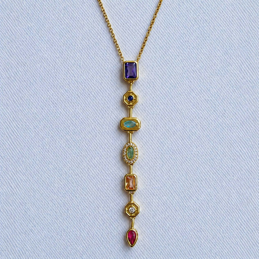 A close-view of a gold-plated stainless steel chain for women featuring a vertical lariat pendant set with various colorful geometric stones