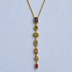 A close-view of a gold-plated stainless steel chain for women featuring a vertical lariat pendant set with various colorful geometric stones