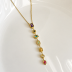 A gold-plated stainless steel chain for women featuring a vertical lariat pendant set with various colorful geometric stones
