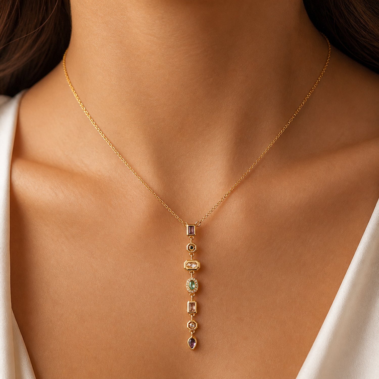 A gold-plated stainless steel chain for women featuring a vertical lariat pendant set with various colorful geometric stones, shown on a model