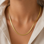 Gold necklace on a person wearing a beige top