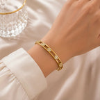 A gold-plated dual-band cuff bangle for women featuring four-petal clover crystal motifs and a secure side-hinge clasp, shown on a model