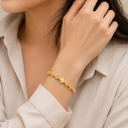 A gold-plated link bangle for women featuring a continuous row of clover motifs with crystal centers and a secure clasp, shown on a model