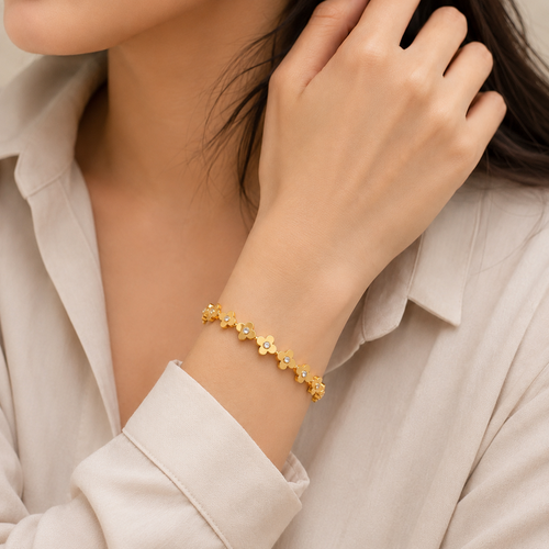 A gold-plated link bangle for women featuring a continuous row of clover motifs with crystal centers and a secure clasp, shown on a model