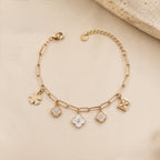 A close-view of a gold-plated chain bracelet for women featuring paperclip links and five floral and clover-themed charms with crystal and pearl accents.