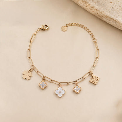 A close-view of a gold-plated chain bracelet for women featuring paperclip links and five floral and clover-themed charms with crystal and pearl accents.
