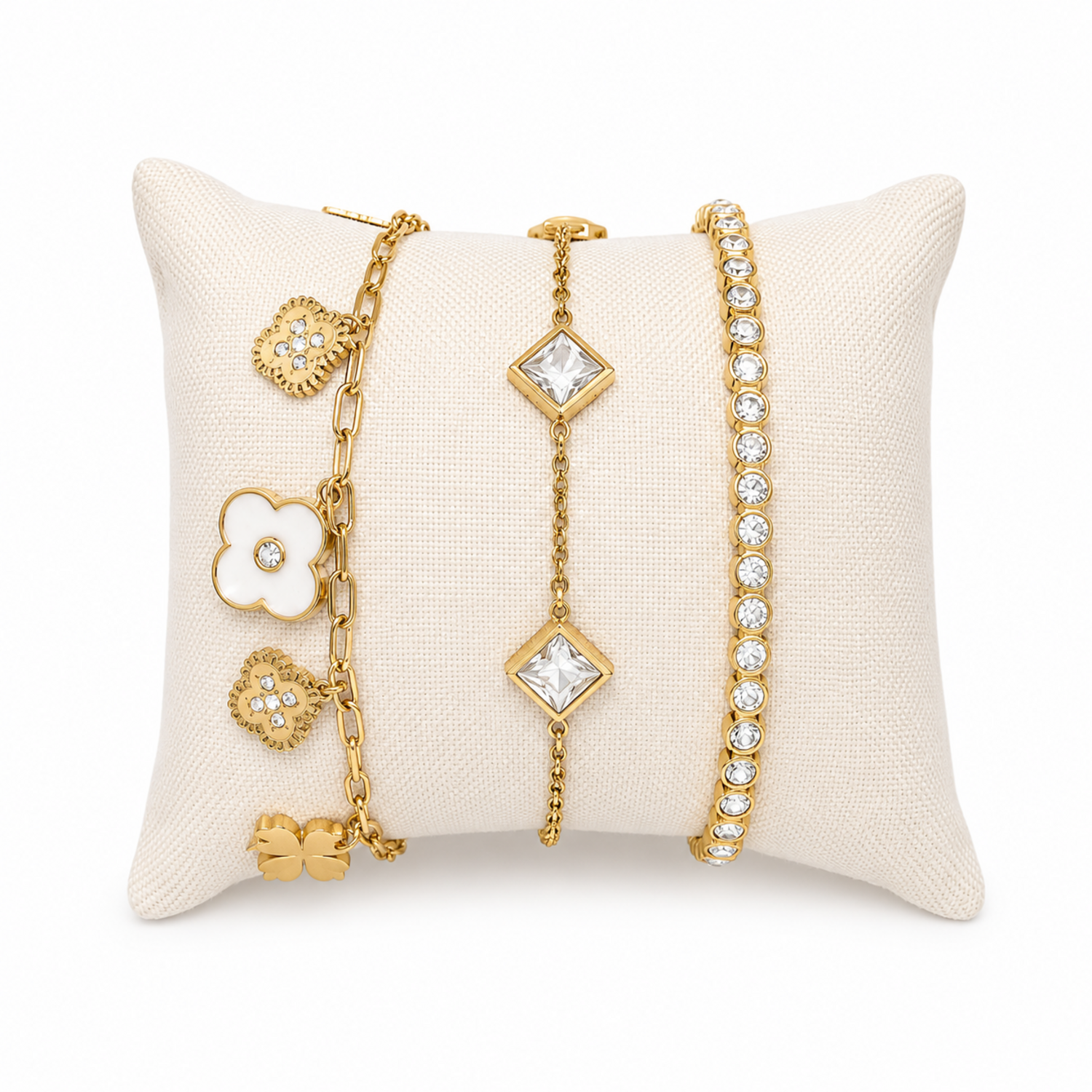A premium three-piece gold-plated bracelet stack for women featuring a white enamel clover paperclip chain, a five-crystal geometric station chain bracelet, and a continuous bezel-set crystal strand