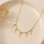 A gold-plated stainless steel chain for women featuring a crystal tennis-style necklace with five dangling hammered-gold coin charms