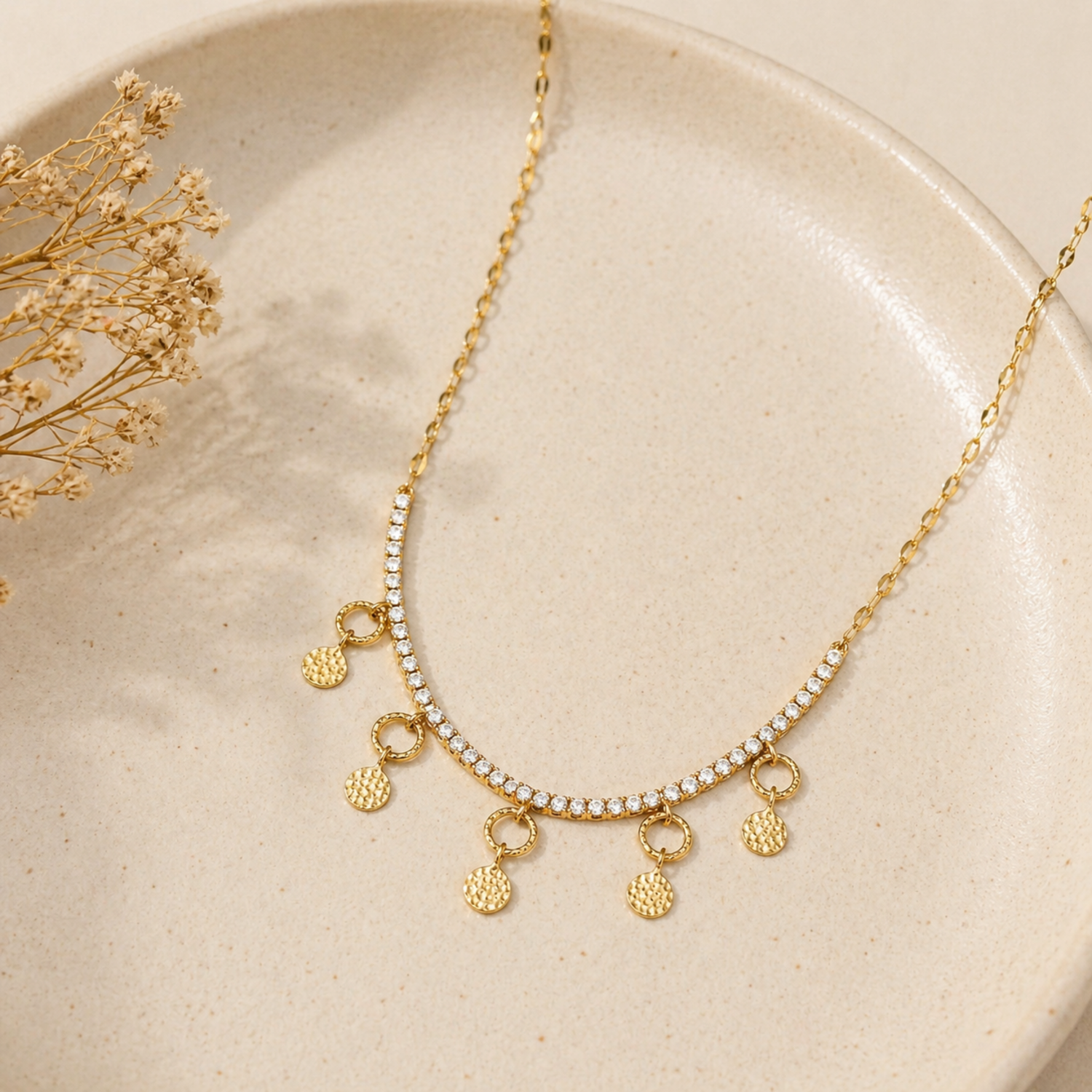 A gold-plated stainless steel chain for women featuring a crystal tennis-style necklace with five dangling hammered-gold coin charms