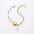 A gold-plated ladies bracelet featuring a gold paperclip chain on one side and a colorful beaded pearl strand with a shell charm on the other.