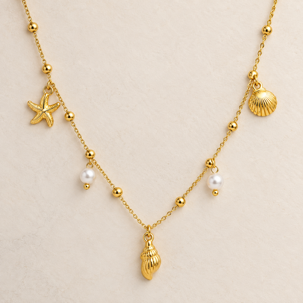Coralie gold coastal necklace for women with shell, starfish and pearl charms on a delicate chain