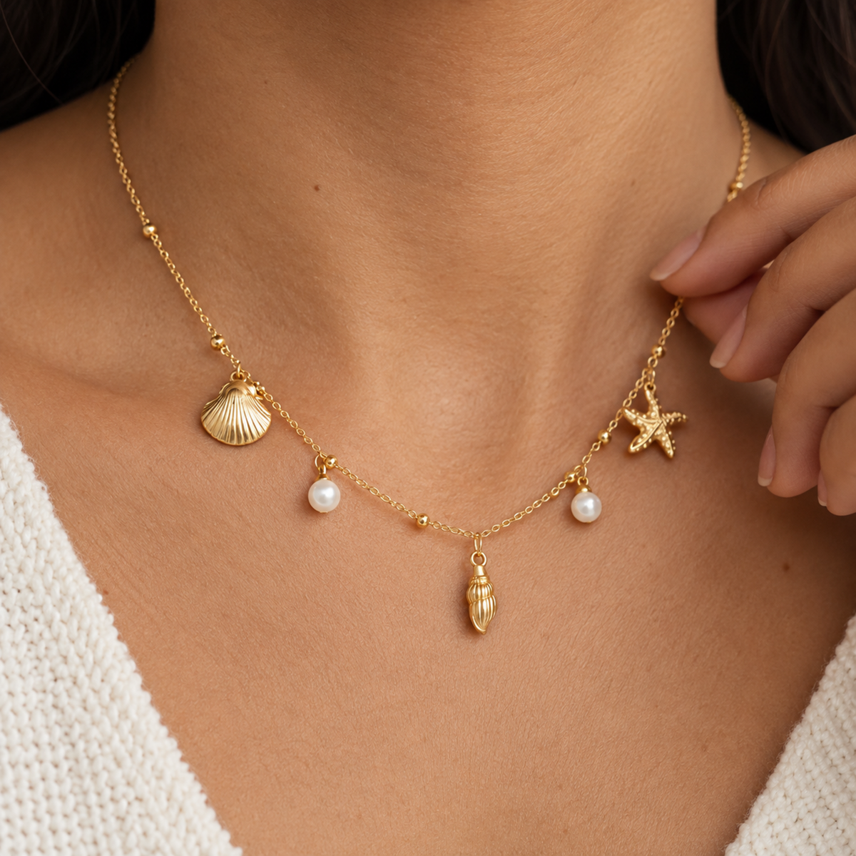 Coralie gold coastal necklace for women with shell, starfish and pearl charms on a delicate chain on a model