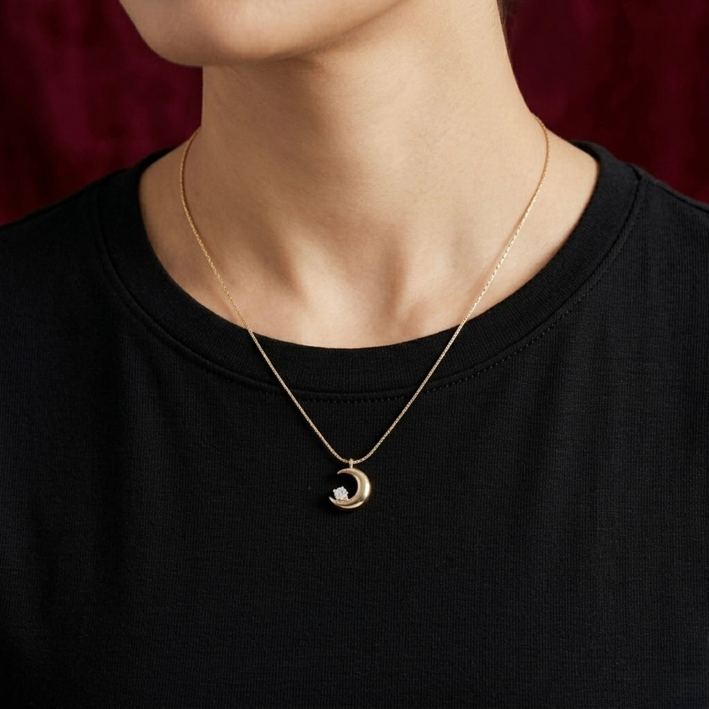 A gold-plated stainless steel chain for women featuring a polished crescent moon pendant set with a single sparkling clear crystal shown on a model