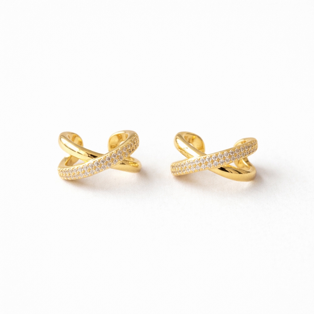 A pair of gold-plated criss-cross double-band ear cuff earrings for women featuring interlinked smooth and pavé crystal bands on a white background