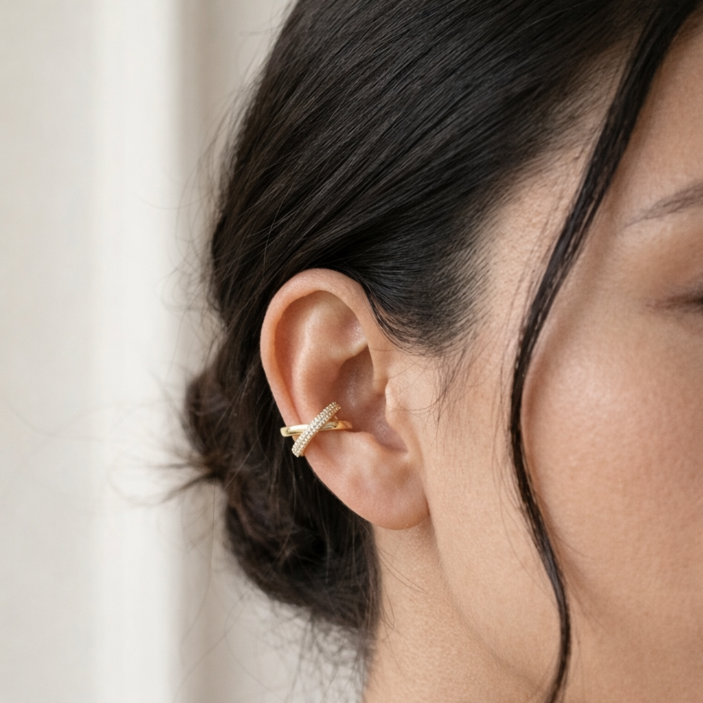 A gold-plated criss-cross double-band ear cuff earrings for women featuring interlinked smooth and pavé crystal bands on a model