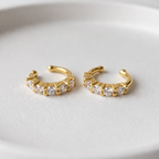 A pair of gold-plated ear cuff earrings for women featuring five brilliant prong-set stones on a white background.