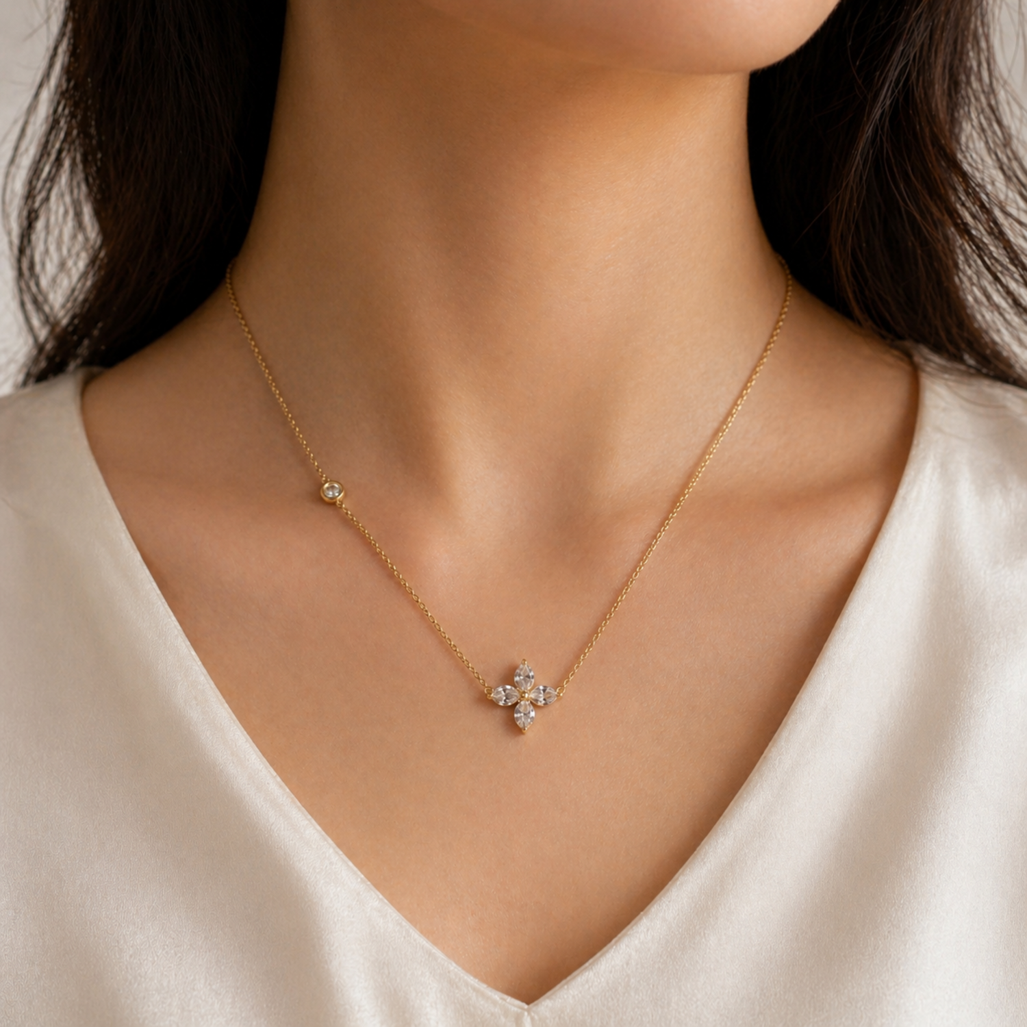 A gold-plated stainless steel chain for women featuring a four-petal crystal flower pendant and a side bezel-set crystal accent, shown on a model