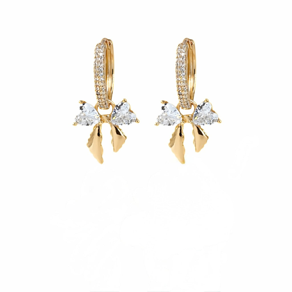A pair of gold-plated hoop earrings for women featuring a crystal bow drop with heart-shaped stones, shown on a white background.