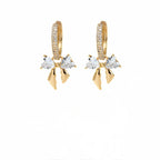 A pair of gold-plated hoop earrings for women featuring a crystal bow drop with heart-shaped stones, shown on a white background.