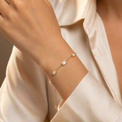 A close-view of a gold-plated stainless steel chain bracelet for women featuring five clear rectangular baguette stones.