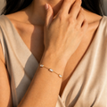 A gold-plated stainless steel chain bracelet for women featuring five clear rectangular baguette stones, shown on a model