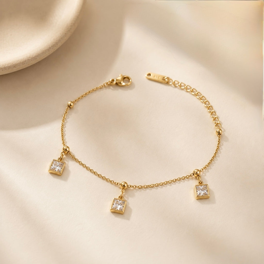 Gold bracelet with square charms on a beige background