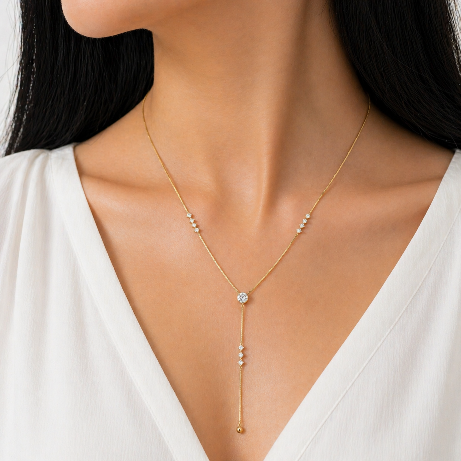 A gold-plated stainless steel chain for women featuring a Y-drop design with multiple crystal accents and a gold bead finish, shown on a model