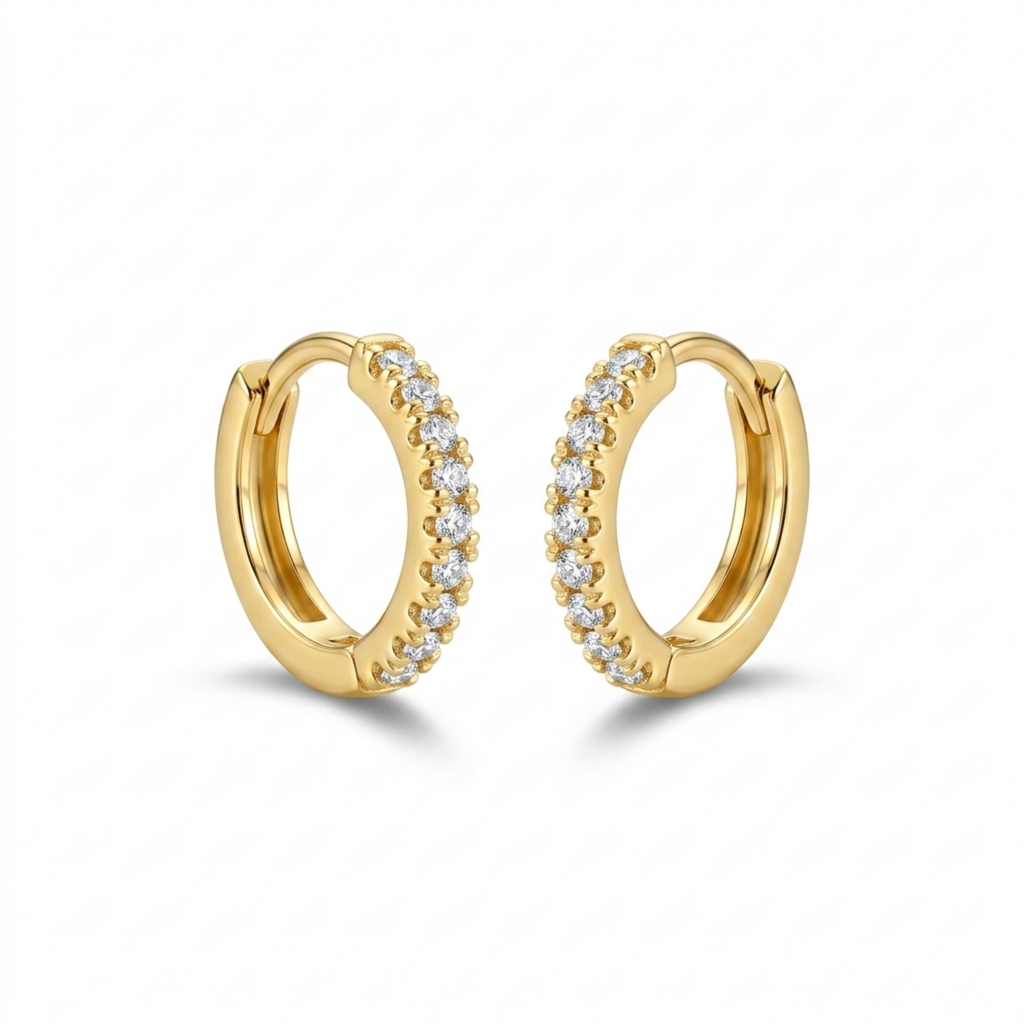 A pair of gold-plated huggie hoop earrings for women featuring a delicate row of clear crystals, shown on a white background