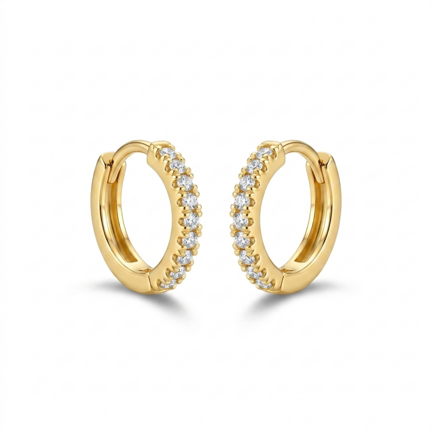 A pair of gold-plated huggie hoop earrings for women featuring a delicate row of clear crystals, shown on a white background