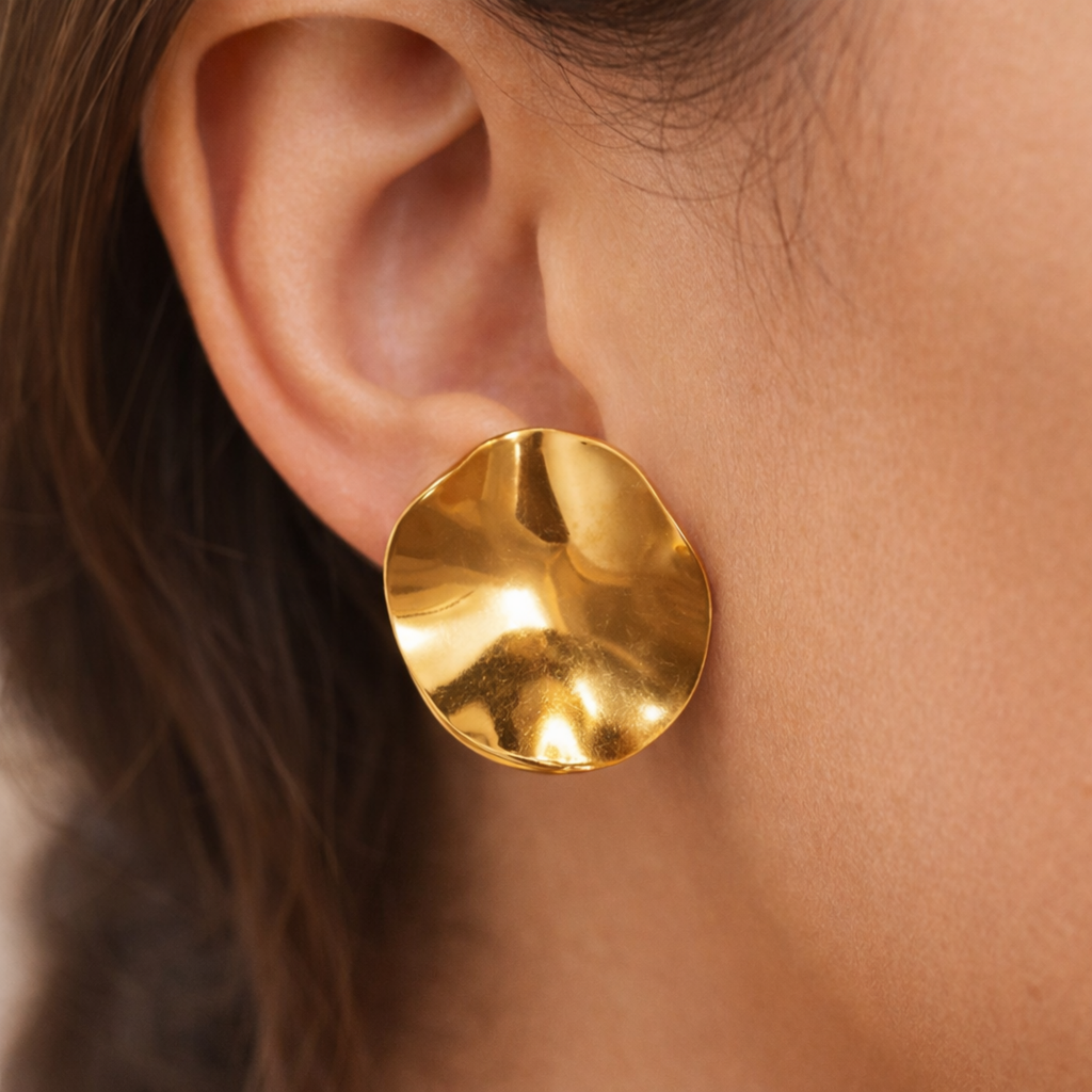 A large, gold-plated sculptural petal stud earrings for women, displayed on a model