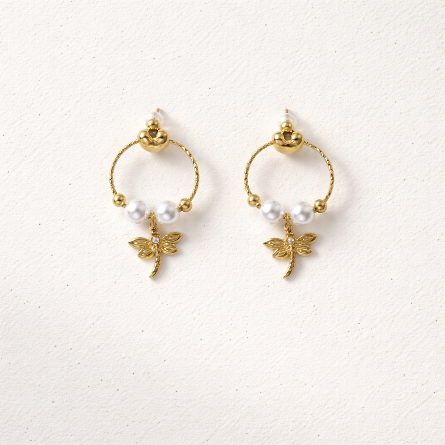 A pair of gold-plated earrings for women featuring a detailed dragonfly charm and three white pearls