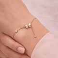 A dainty gold-plated chain bracelet for women featuring a white butterfly charm and crystal accents on a model