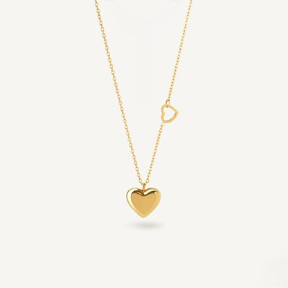 A close-view of a gold-plated stainless steel chain for women featuring a polished 3D heart pendant and a smaller open-heart charm integrated into the side of the chain