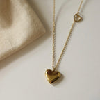 A close-view of a gold-plated stainless steel chain for women featuring a polished 3D heart pendant and a smaller open-heart charm integrated into the side of the chain
