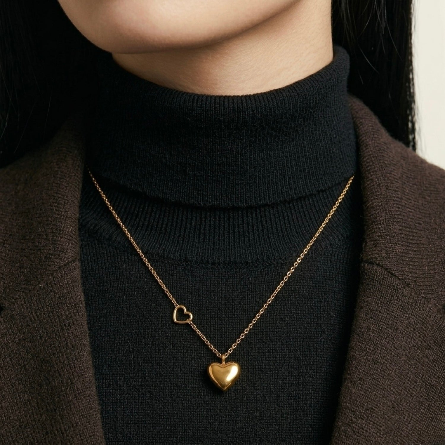 A gold-plated stainless steel chain for women featuring a polished 3D heart pendant and a smaller open-heart charm integrated into the side of the chain shown on a model