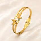 A gold-plated dual-strand cuff bangle for women featuring two frosted butterfly charms and small crystal accents.