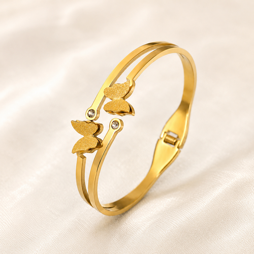 A gold-plated dual-strand cuff bangle for women featuring two frosted butterfly charms and small crystal accents.