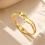 A close-view of a gold-plated dual-strand cuff bangle for women featuring two frosted butterfly charms and small crystal accents.