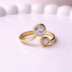 Gold plated adjustable ring for women featuring two heart-cut white stones of different sizes in a bypass wrap design, displayed on a white surface