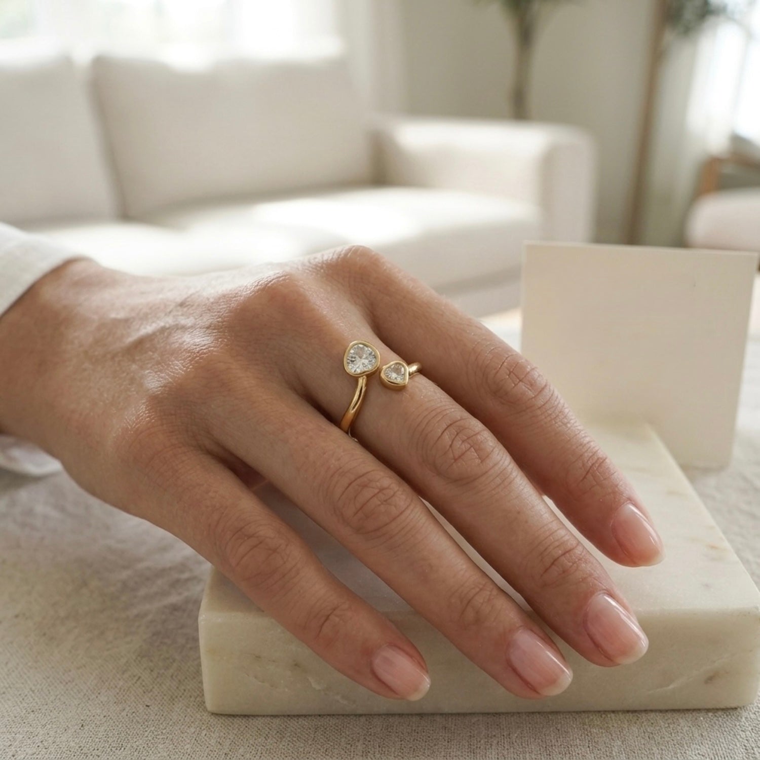 Gold plated adjustable ring for women featuring two heart-cut white stones of different sizes in a bypass wrap design, displayed on a model hand