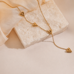 A close-view of a gold-plated stainless steel chain for women featuring a Y-shaped drop design with four polished, 3D heart charms