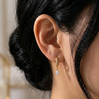 A gold-plated hoop earrings for women featuring a sparkling pear-cut crystal drop, shown on a model