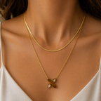 Gold plated layered necklace with a floral pendant on a model wearing a white top.