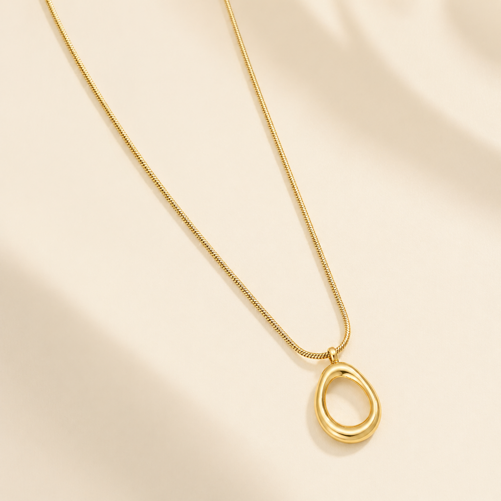 A close-view of a gold-plated stainless steel chain for women featuring a sleek snake link and a open-oval pendant