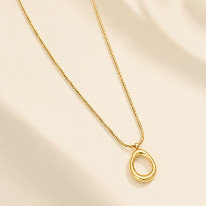 A close-view of a gold-plated stainless steel chain for women featuring a sleek snake link and a open-oval pendant
