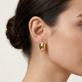 A gold-plated oval dome stud earrings for women, shown on a model