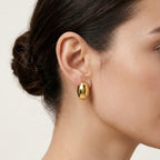 A gold-plated oval dome stud earrings for women, shown on a model