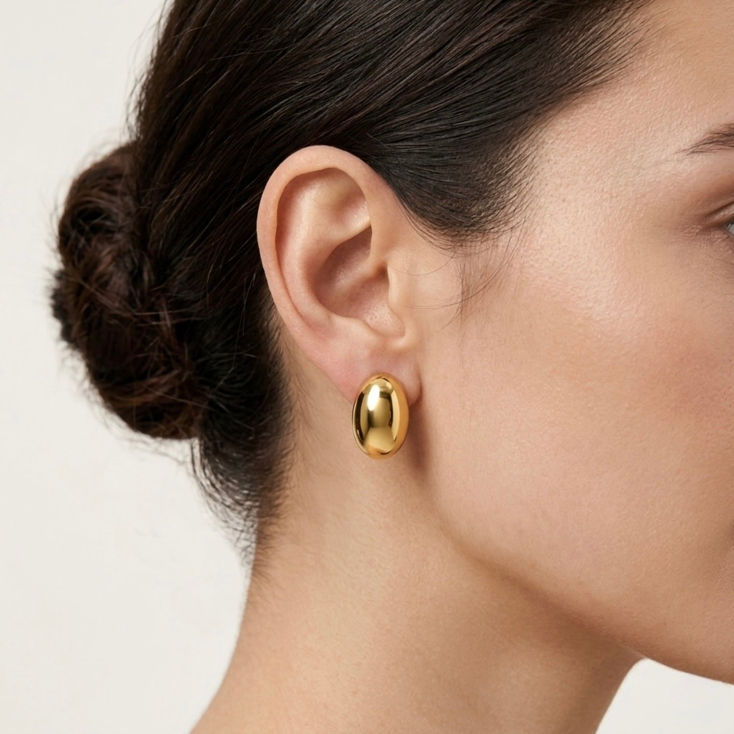 A gold-plated oval dome stud earrings for women, shown on a model